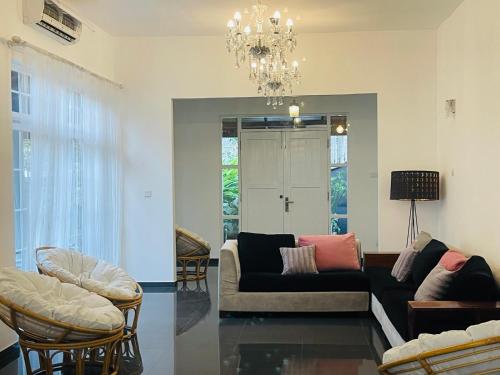 a living room with a couch and chairs and a chandelier at Roshe-Sky Guest House Colombo in Mahabage