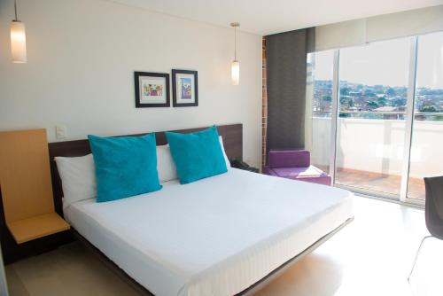 a bedroom with a large white bed with blue pillows at Hotel CasaBlanca Cucuta in Cúcuta