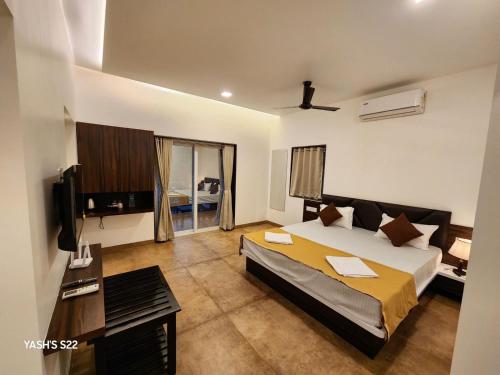 a bedroom with a bed and a desk and a television at Basil Leaf Resort in Alibag