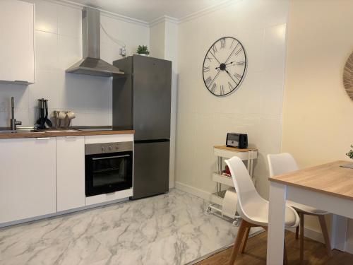 eine Küche mit einem Kühlschrank aus Edelstahl und einer Uhr an der Wand in der Unterkunft Apartamento Cueto II in Soto del Barco