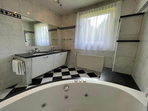 a bathroom with a tub and a sink and a mirror at Haus Landruhe in Greifenburg