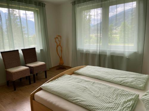a bedroom with a bed and two chairs and a window at Haus Landruhe in Greifenburg