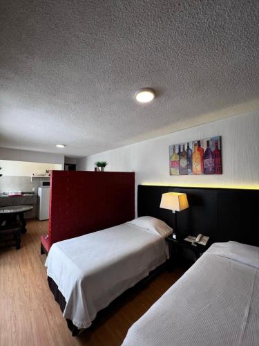 een slaapkamer met twee bedden en een tafel met een lamp bij Suites Havre in Mexico-Stad