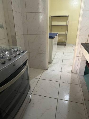 a kitchen with a stove and a tiled floor at Julia Acomodações in Cabo Frio