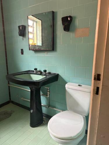a bathroom with a toilet and a sink at Julia Acomodações in Cabo Frio
