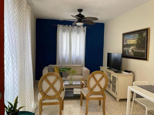 Gloria’s Cozy Apartment في لا رومانا: غرفة معيشة مع أريكة ومروحة سقف