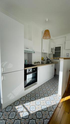 une cuisine avec des armoires blanches et un four noir dans l'établissement La Jacinthe Saint-Ouen, à Saint-Denis