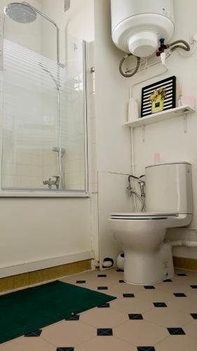une salle de bain avec toilettes et douche en verre dans l'établissement La Jacinthe Saint-Ouen, à Saint-Denis