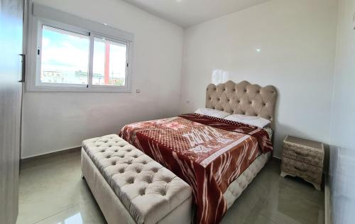 a bedroom with a bed with a couch and a window at Superbe appartement avec une vue panoramique sur piscine in Cabo Negro