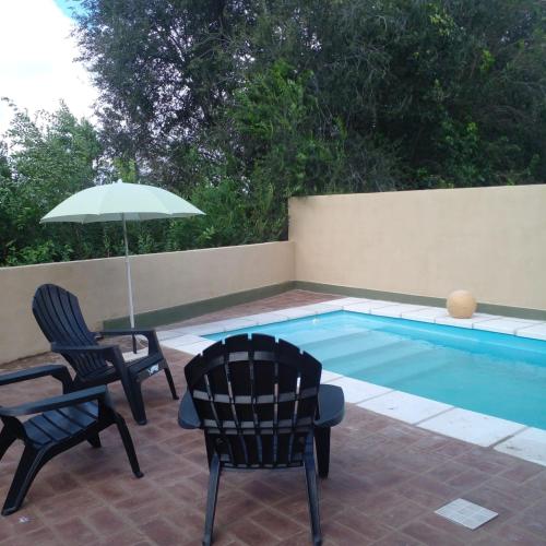 two chairs and an umbrella next to a swimming pool at PUEBLO MIO in Cosquín
