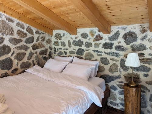 a bed in a room with a stone wall at Kompleks Etno Luks 