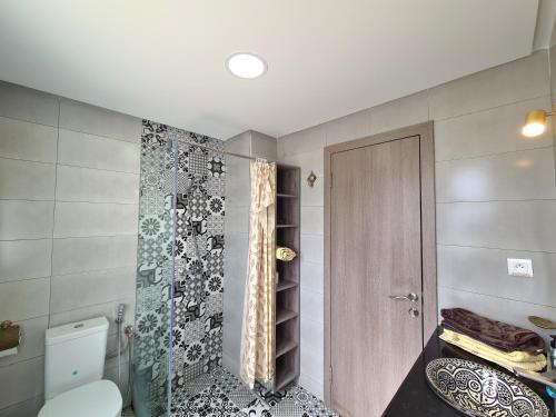 a bathroom with a toilet and a glass shower door at Superbe appartement avec une vue panoramique sur piscine in Cabo Negro