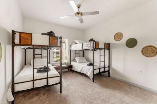two bunk beds in a room with a ceiling fan at Cozy 2Bed Boho Hideaway 10 Min to Parks Allows Pet in Orlando