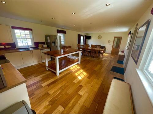 a kitchen and living room with a wooden floor and a table at Sherrabeg Cottage in Newtonmore