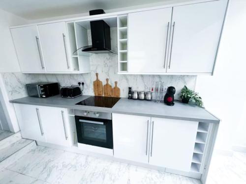 a white kitchen with white cabinets and a stove at Modern Luxury 2 Bed with Parking in Catford
