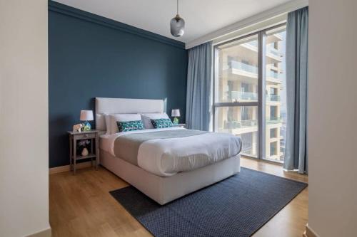 a bedroom with a large bed with blue walls at Frank Porter - Boulevard Point in Dubai