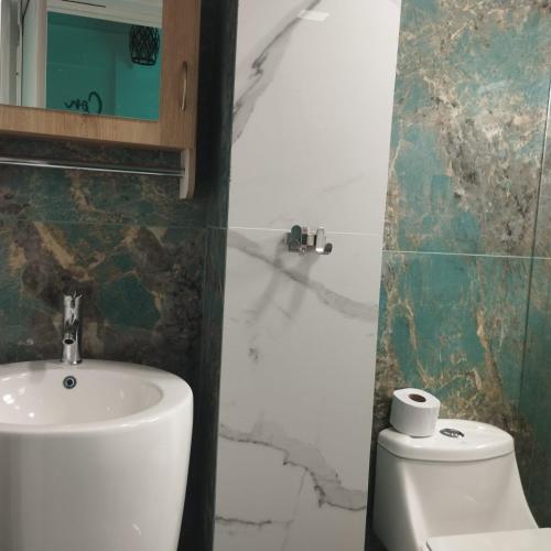 a bathroom with a sink and a toilet and a mirror at HOTEL DE LOS COLORES in El Queremal