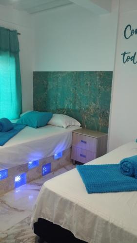 two beds with lights on them in a room at HOTEL DE LOS COLORES in El Queremal