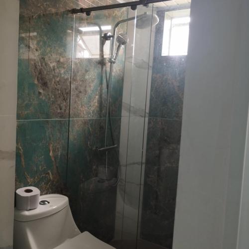 a bathroom with a toilet and a glass shower at HOTEL DE LOS COLORES in El Queremal