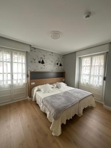 um quarto com uma cama grande e 2 janelas em Hotel El Pescador em Tazones