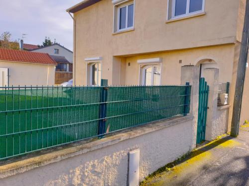 a house with a green fence in front of it at Maison hyper calme proche RER, à 2 arrêts du Stade de France, 25min Paris centre, proche, Disney, Astérix, CDG in Stains