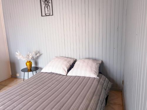 a bedroom with a bed and a vase on a table at Maison hyper calme proche RER, à 2 arrêts du Stade de France, 25min Paris centre, proche, Disney, Astérix, CDG in Stains