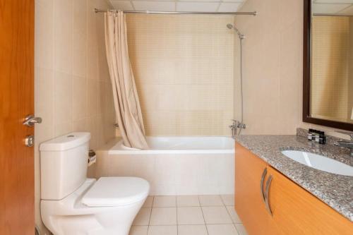 a bathroom with a toilet and a tub and a sink at Frank Porter - Suburbia in Dubai