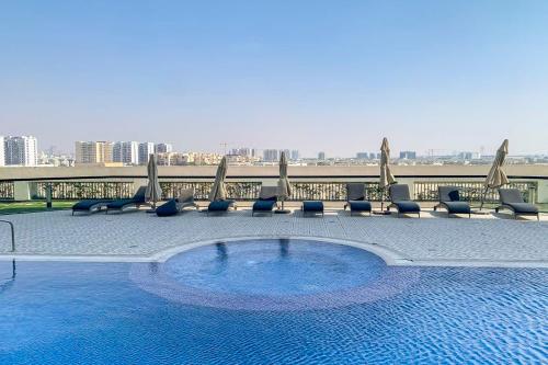 a swimming pool with chairs and umbrellas on a building at Frank Porter - Starz by Danube in Dubai