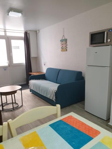 - un salon avec un canapé bleu et un réfrigérateur dans l'établissement Saint Laurent de la Salanque Charmant T2 classé 3 étoiles, à Saint-Laurent-de-la-Salanque