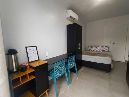 a small bedroom with a bed and two chairs at Casa Container Azul Mariscal in Bombinhas