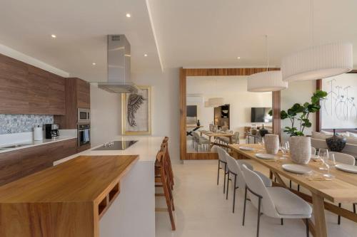 カボ・サン・ルーカスにあるLuxurious New 3BR Condo with Ocean and Arch Viewsの長いテーブルと椅子のあるキッチンとダイニングルーム