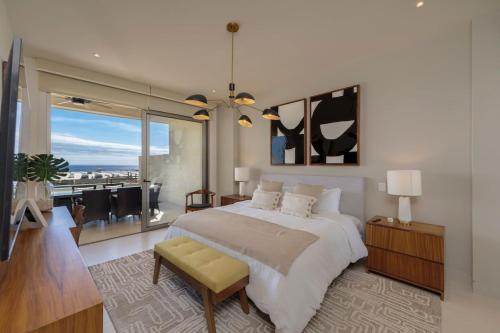 a bedroom with a large bed and a living room at Luxurious New 3BR Condo with Ocean and Arch Views in Cabo San Lucas