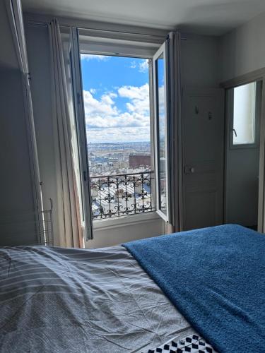 een slaapkamer met een blauw bed en een groot raam bij Spacieux appartement à 50m du Sacre Coeur - Magnifique Vue in Parijs