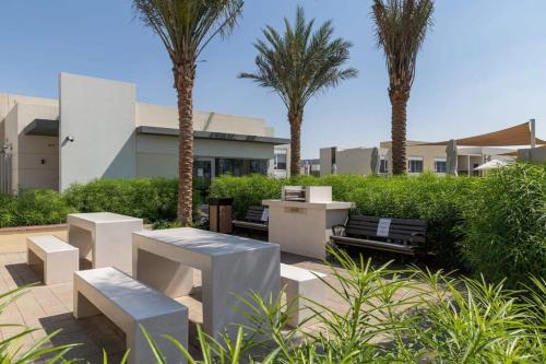 a patio with benches and palm trees in front of a building at Frank Porter - Urbana II in Dubai