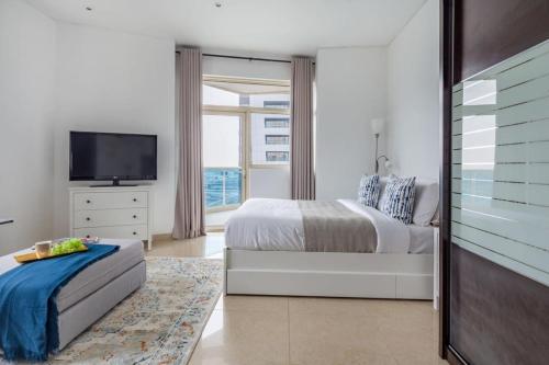 a white bedroom with a bed and a television at Frank Porter - Yacht Bay in Dubai