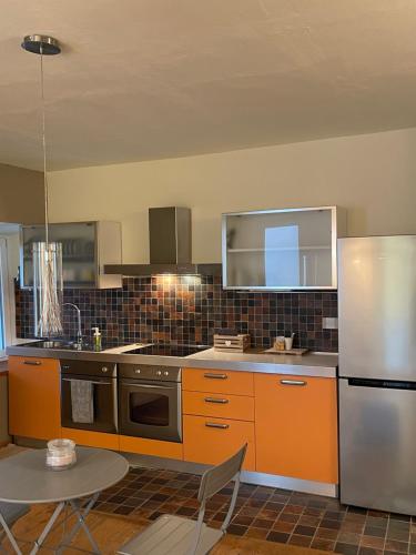 a kitchen with orange cabinets and a stainless steel refrigerator at La Quintessenza del Borgo in Varzi