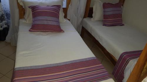 two beds with striped pillows on them in a room at Tranquil Pendo villas in Diani Beach
