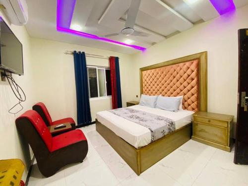 - une chambre avec un lit et une chaise rouge dans l'établissement Executive Guest House, à Islamabad