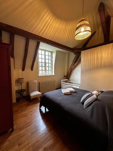 une chambre avec un grand lit et un lustre dans l'établissement Le Vieux Manoir, à Amboise