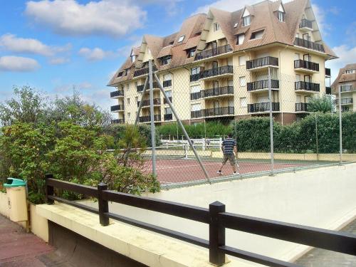 カブールにあるAppartement d'une chambre a Cabourg a 100 m de la plage avec piscine partagee jardin amenage et wifiの建物前のテニスコートを歩く男