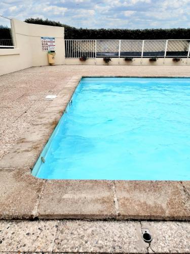 une piscine bleue en face d'un bâtiment dans l'établissement Appartement charmant à Cabourg avec piscine partagée (24 m²), à Cabourg