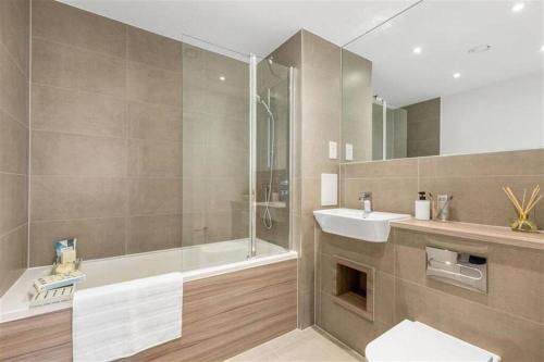 a bathroom with a shower and a sink and a tub at Stylish & Spacious 1 Bed Apartment in Barking