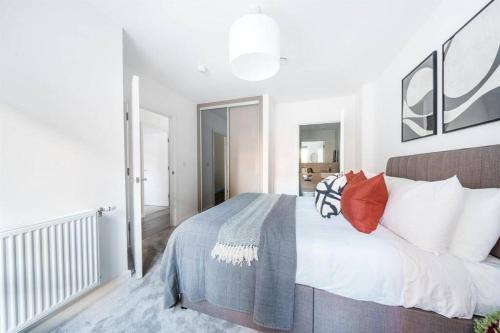 a white bedroom with a large bed with red pillows at Stylish & Spacious 1 Bed Apartment in Barking