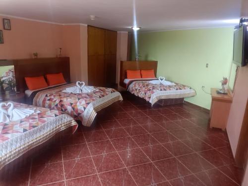 Habitación con 3 camas con almohadas de color naranja en Hotel El Ceibo, en Macuto