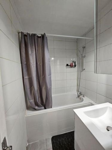 une salle de bain blanche avec une baignoire et un lavabo dans l'établissement Bel appartement à Choisy-le-roi, à Choisy-le-Roi