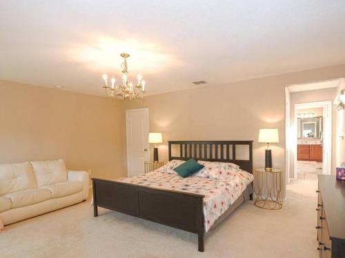 a bedroom with a bed and a couch and a chandelier at A Charming Hill Country Home in Boerne