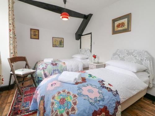 een slaapkamer met 2 bedden en een stoel bij Blackbird Cottage in Bideford