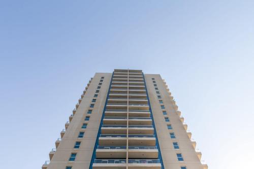 a tall white building with a blue sky in the background at Frank Porter - Mayfair Residency in Dubai