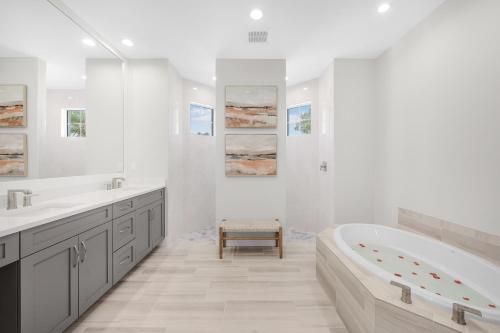 a white bathroom with a tub and two sinks at 2024 Monsterrat model waterfront home with lap pool in Marco Island