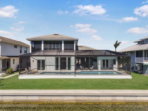 a large white house with a pool in the yard at 2024 Monsterrat model waterfront home with lap pool in Marco Island